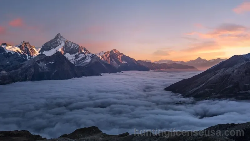 Snow-capped mountain range at dawn overlooking an alpine meadow during deer season